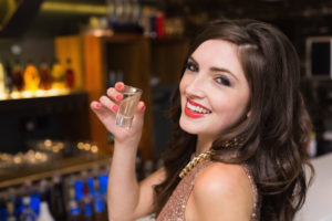 Pretty brunette drinking a shot at the bar